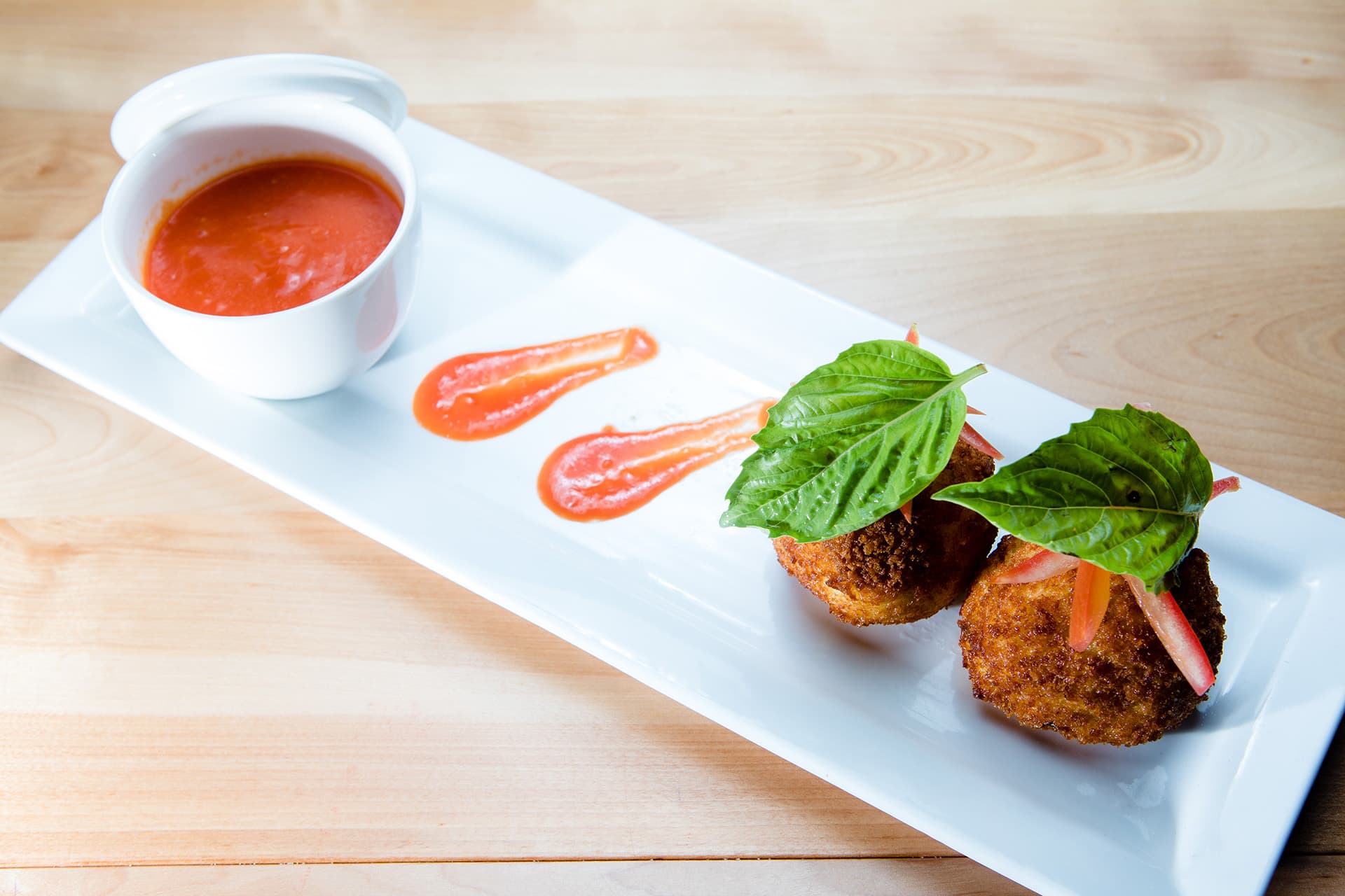 Crispy arancini with a swipe of tomato sauce, plated at Cassariano